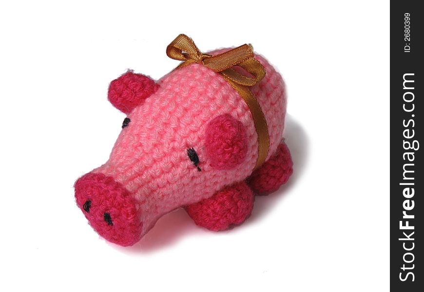 Red crocheted pig with gold bow over white background.