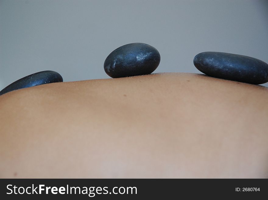 Hot stones relax massage. Girl's back with three hot stones.