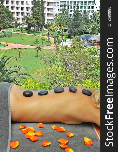 Girl relaxing with hot stones on back. hot stones massage treatment.