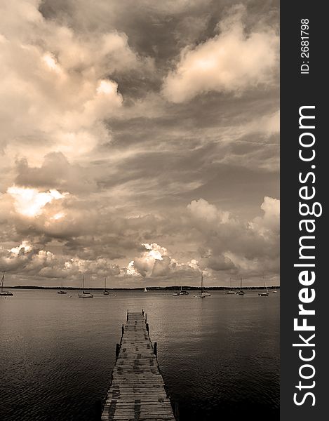 Dock floating in lake with sky and sailboats. Dock floating in lake with sky and sailboats