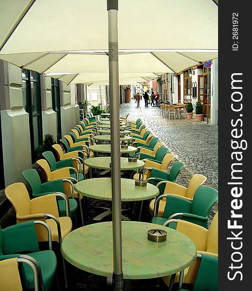 Chairs, tables and parasolars of a cafe in a row.