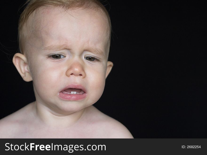 Image of crying toddler sitting in front of a black background