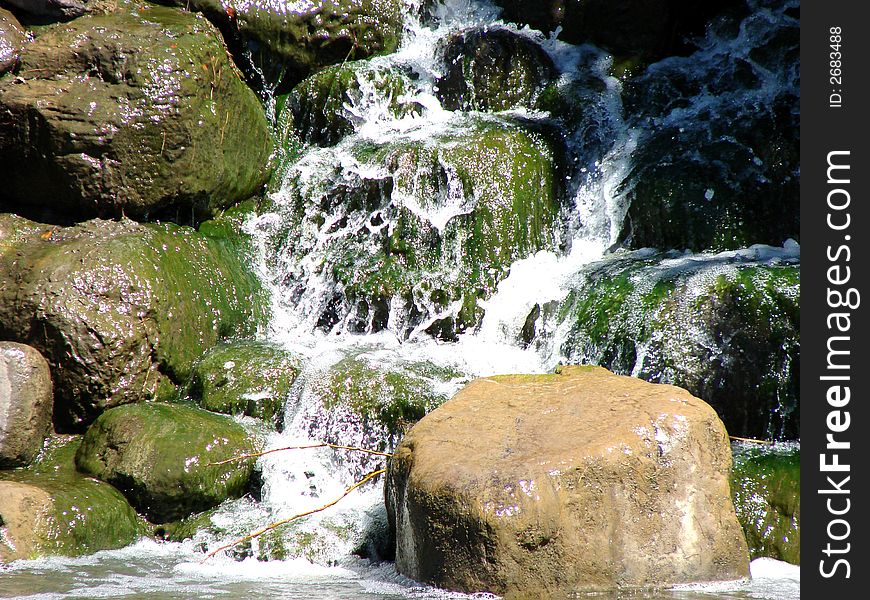 Waterfall flowing over mossy rocks into a pond. Waterfall flowing over mossy rocks into a pond