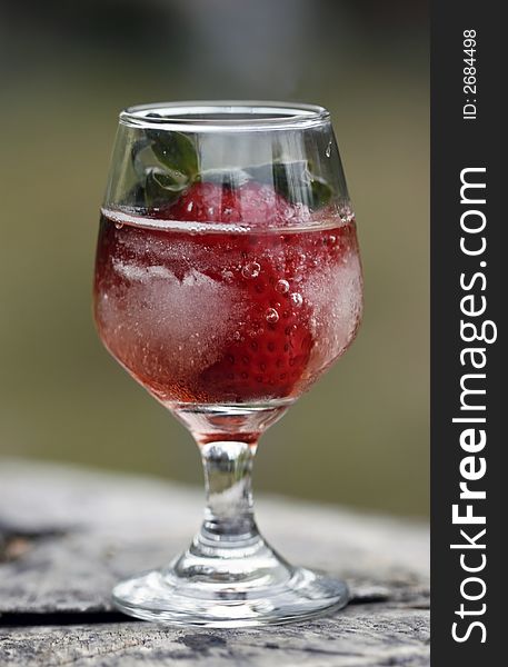 Single strawberry in glass against a natural background. Single strawberry in glass against a natural background