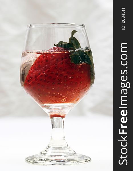 Single strawberry in a glass with ice on white background. Single strawberry in a glass with ice on white background
