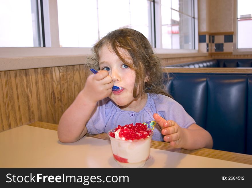 A little girl eating icecream in a restaurant. A little girl eating icecream in a restaurant
