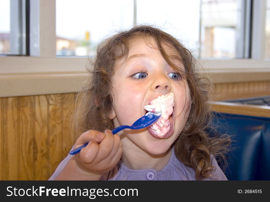 A young girl with a big spoonful of ice cream. A young girl with a big spoonful of ice cream