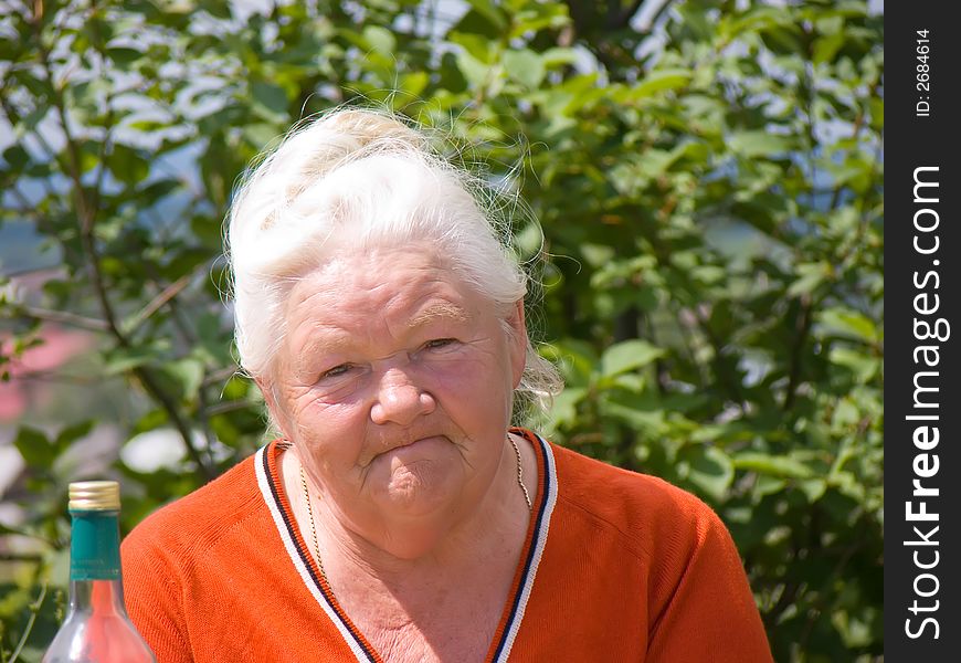 Photo of the elderly woman on a background of green branches. Photo of the elderly woman on a background of green branches