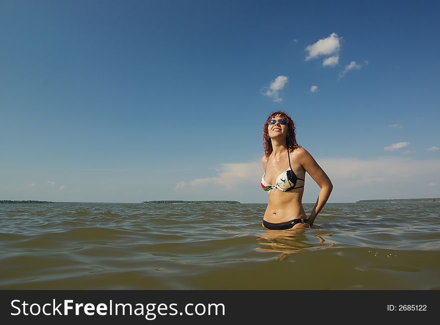 Girl stands in the sea watching up and cloudscape