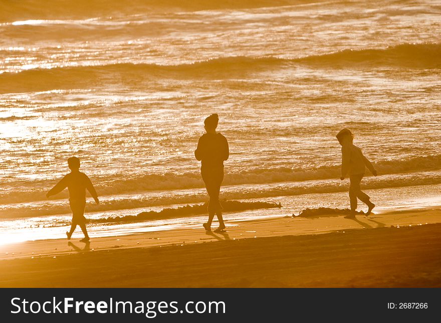 A woman with her two children walking along the beach. A woman with her two children walking along the beach.