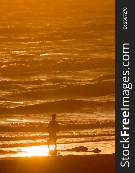 Young boy standing on beach silhouetted by ocean. Young boy standing on beach silhouetted by ocean.