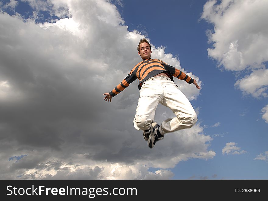 Young man happily jumping against blue sky. Young man happily jumping against blue sky.