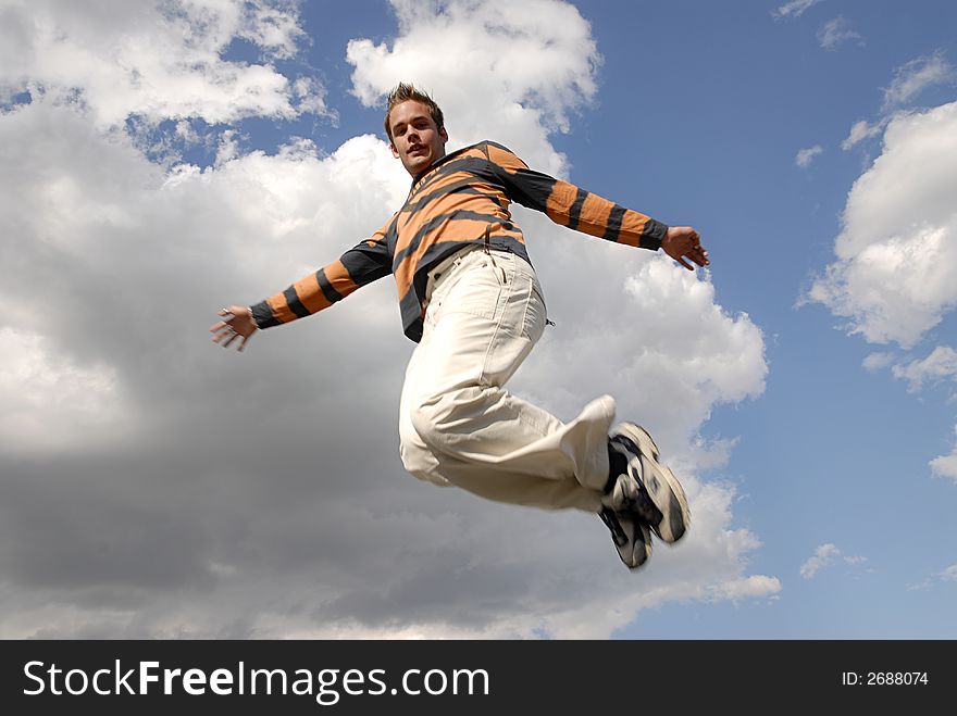 Young man happily jumping against blue sky. Young man happily jumping against blue sky.