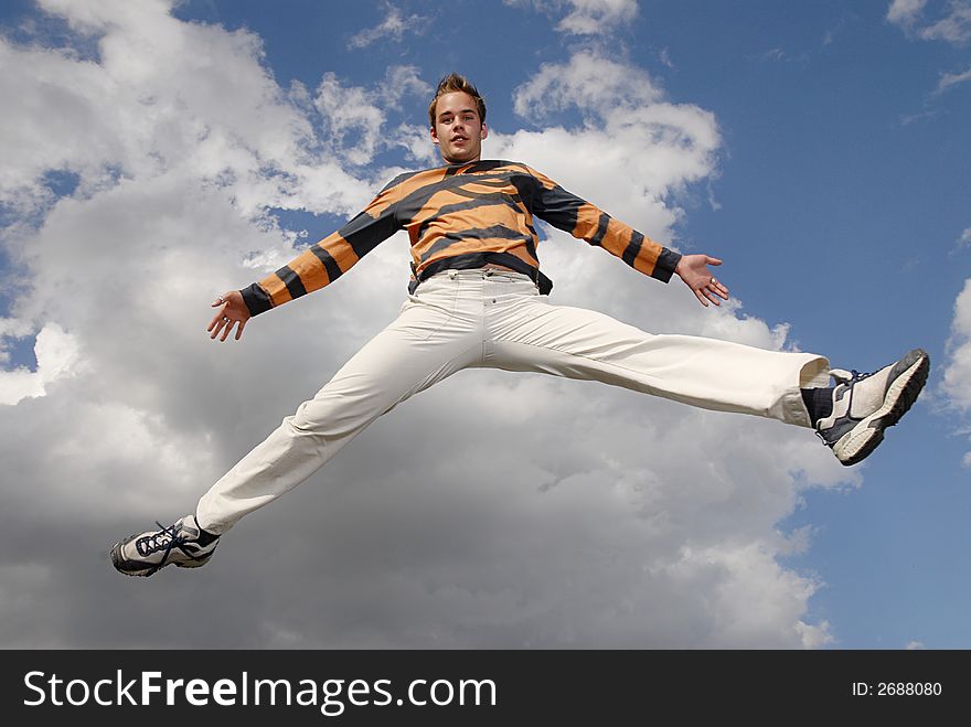 Young man happily jumping against blue sky. Young man happily jumping against blue sky.