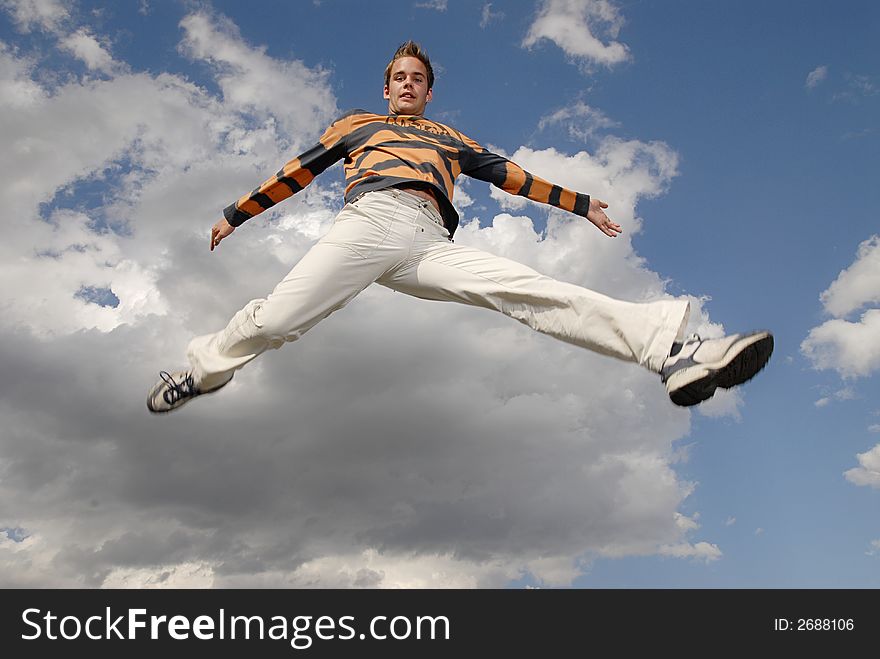 Young man happily jumping against blue sky. Young man happily jumping against blue sky.