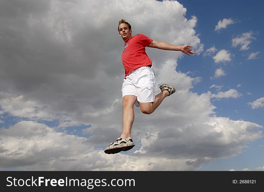 Young man happily jumping against blue sky. Young man happily jumping against blue sky.