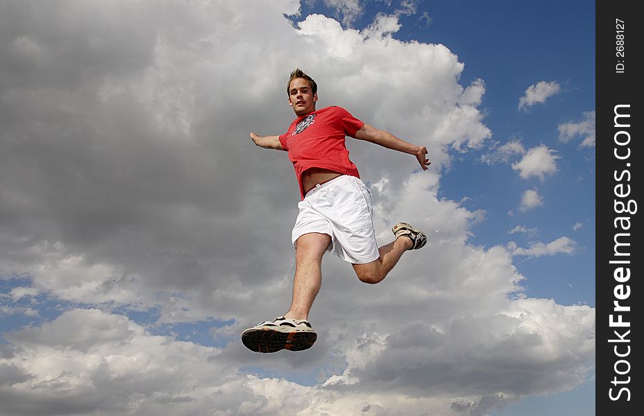 Young man happily jumping against blue sky. Young man happily jumping against blue sky.