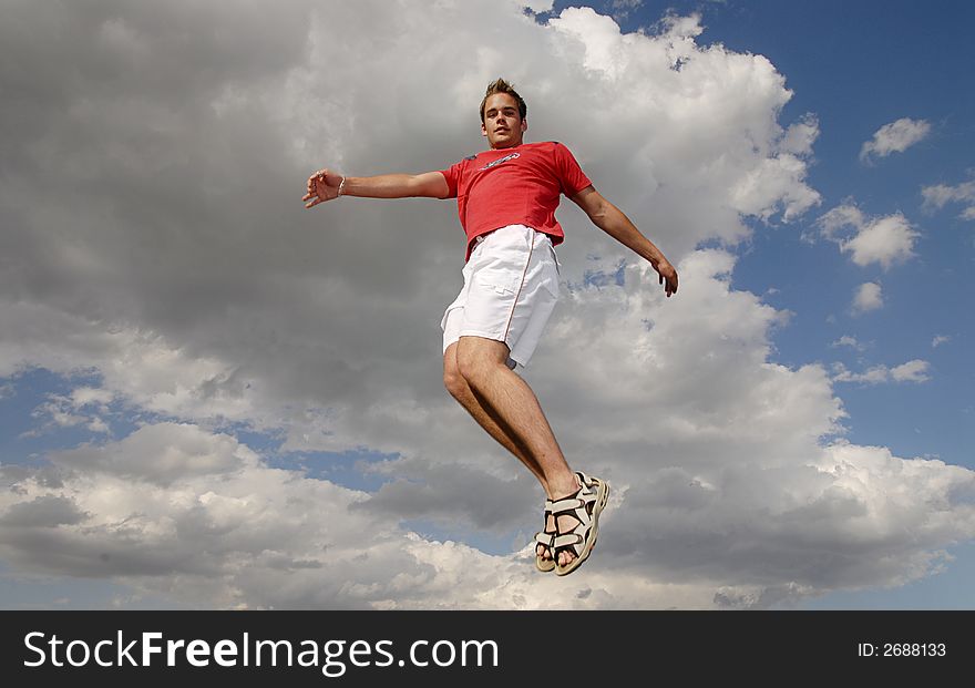 Young man happily jumping against blue sky. Young man happily jumping against blue sky.