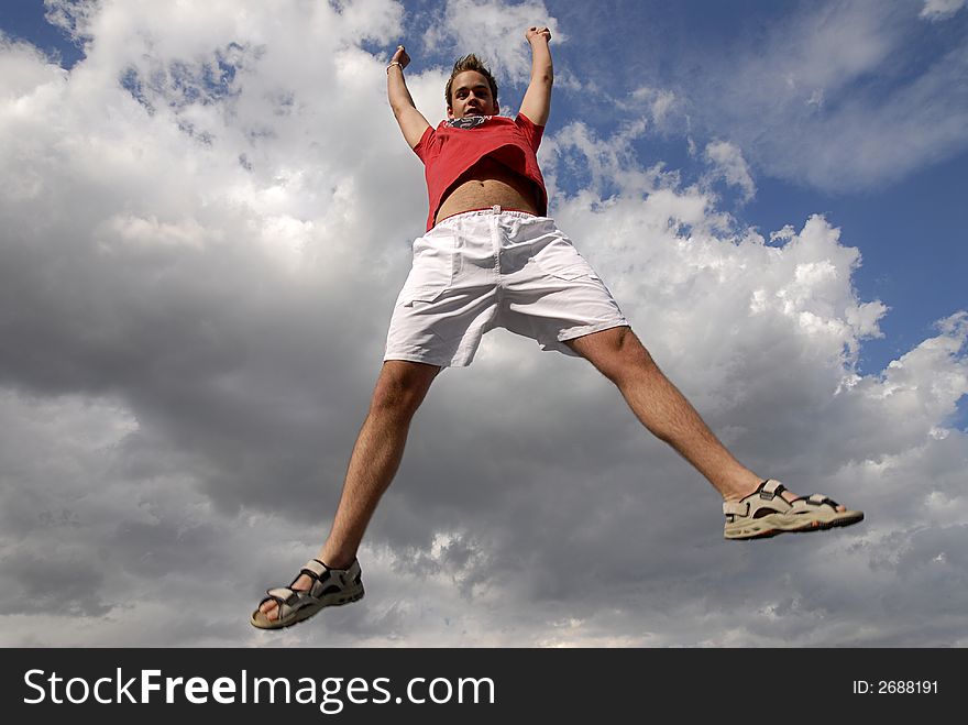 Young man happily jumping against blue sky. Young man happily jumping against blue sky.