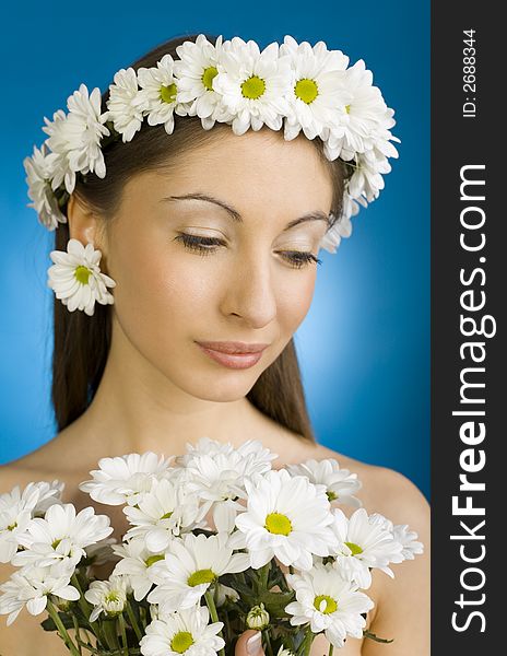 Young, beautiful and  modest woman with bouquet of white flowers. Blue background. Young, beautiful and  modest woman with bouquet of white flowers. Blue background