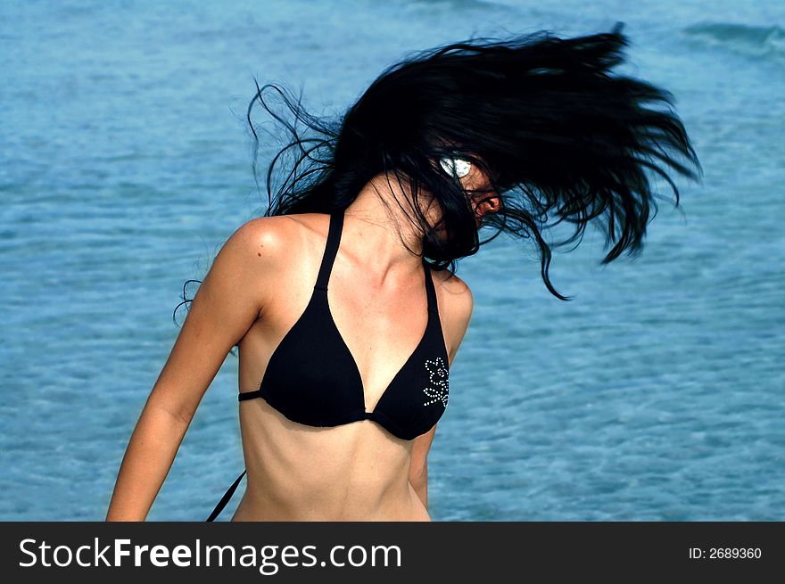 Bikini girl doing hairdance with ocean waves background. Bikini girl doing hairdance with ocean waves background