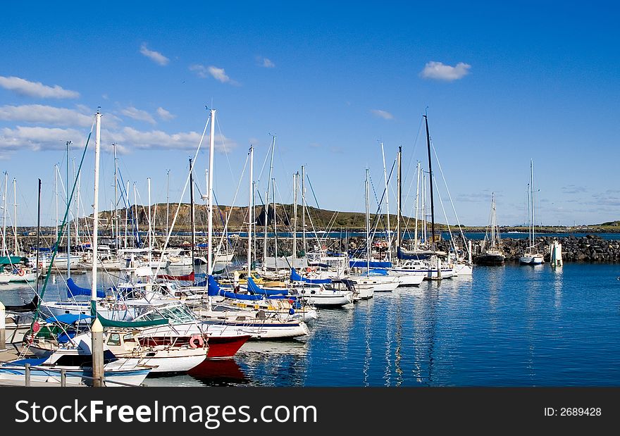 A group of sailing boats moored in a harbour with reflections on the water. A group of sailing boats moored in a harbour with reflections on the water.