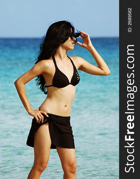 Young tropical girl wearing bikini on beach background. Young tropical girl wearing bikini on beach background