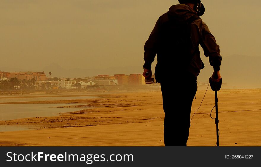 A man uses metal detector to search for gold at the sea shore. A man uses metal detector to search for gold at the sea shore.
