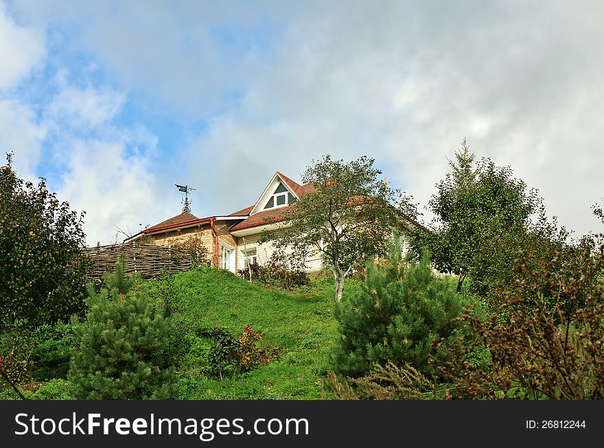 Residential house with red top among trees on the hillside. Residential house with red top among trees on the hillside