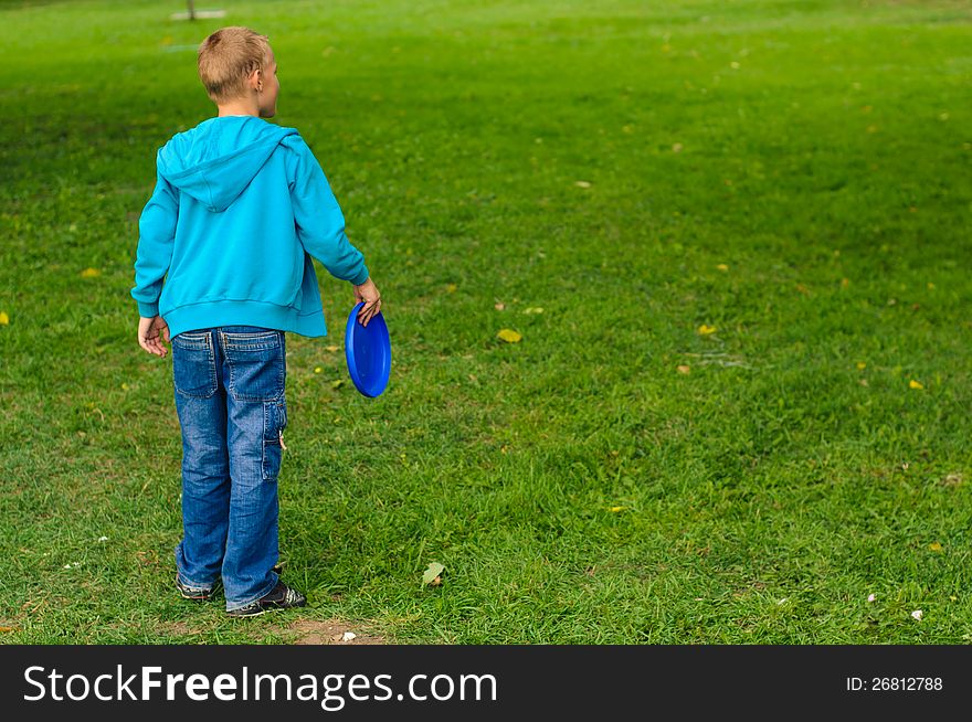 Little boy playing frisbee on green grass