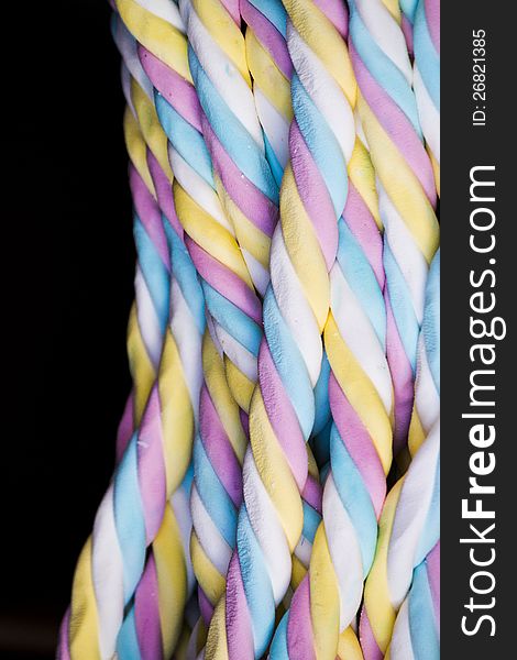 Close up view of some sweet and twisted brightly colored candies against a black background.