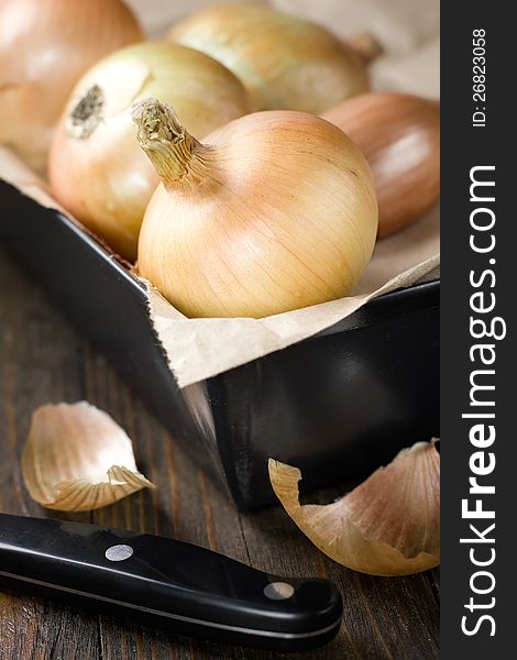 Onions close up in iron box on kitchen table