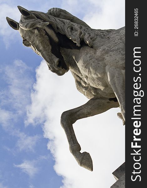 Close view of a stone horse statue over a cloudy blue sky.