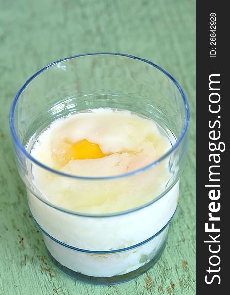 Closeup of a glass with soft boiled eggs on green table