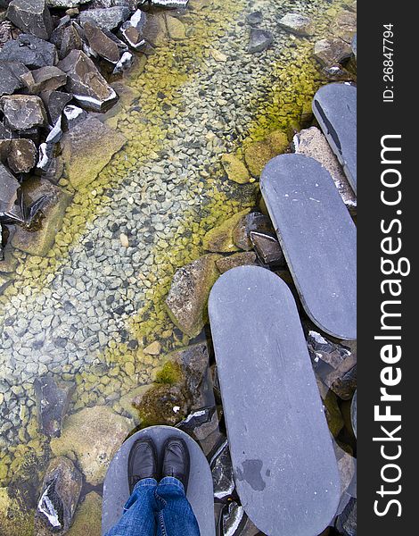 View of a curved step-by-step stone road on a urban park over a lake.