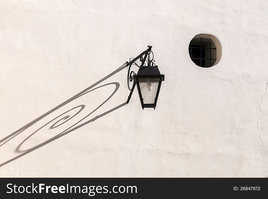 Old lantern on the white wall of a house