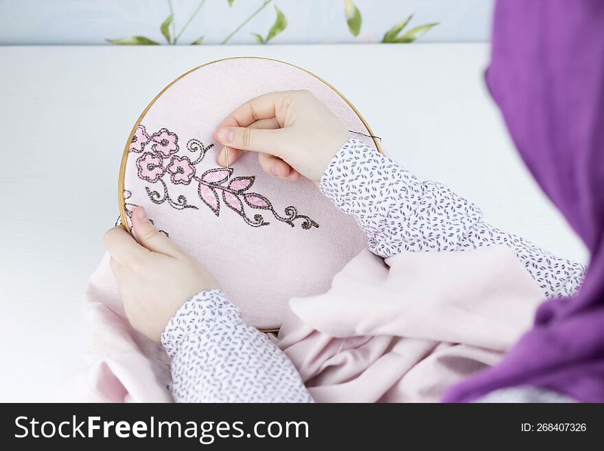 Hand embroidery flowers. Female hands holding hoop, thread mouline. Needlework