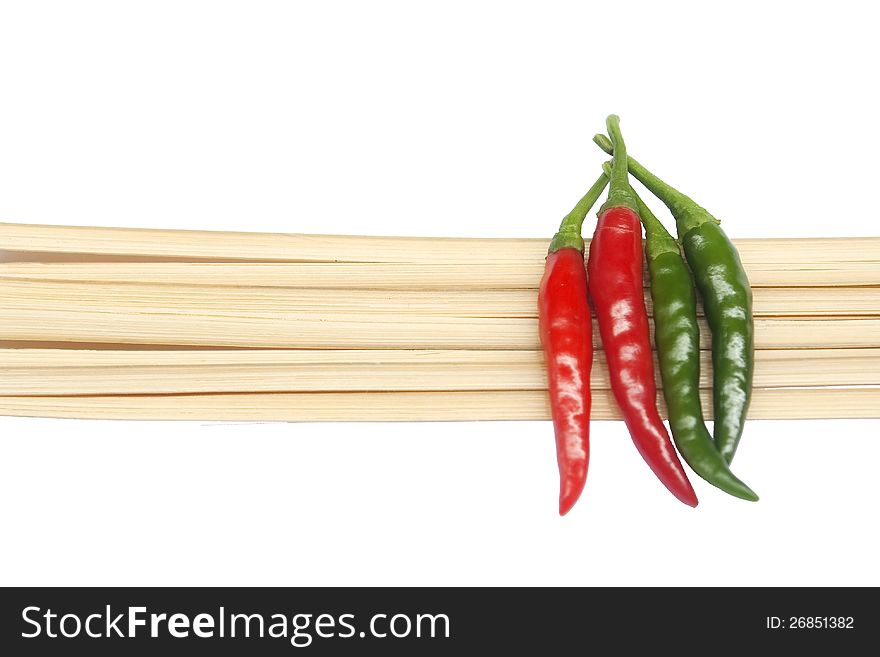 The green and red chilies on thin bamboo stripes with white background
