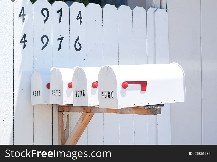 4 mailboxes in front of white fence