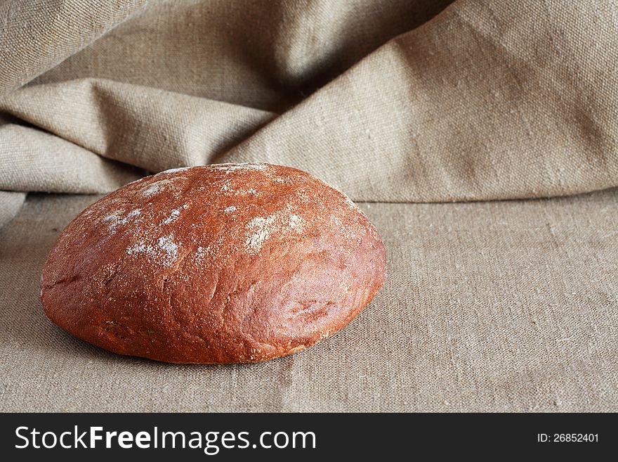 Round rye bread lying on canvas surface with free space for text