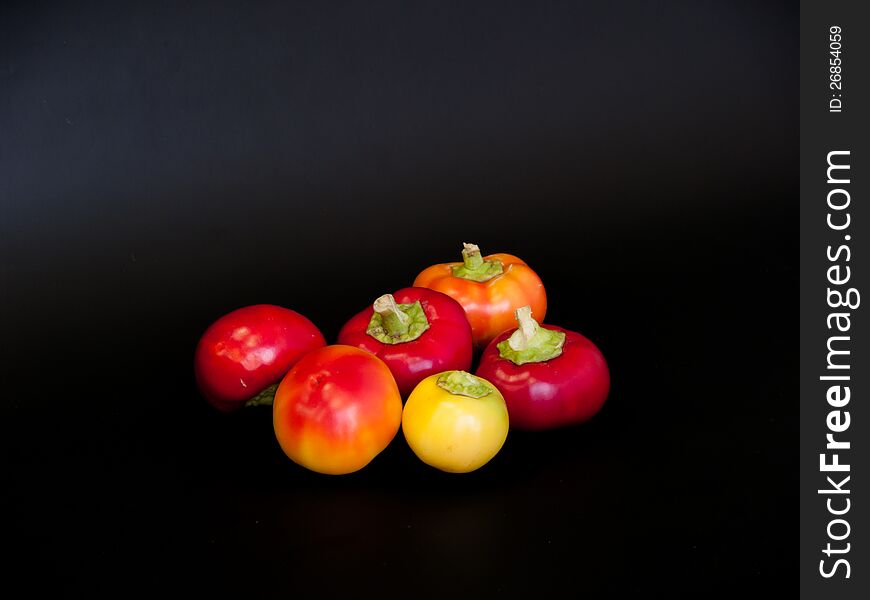Round little colorful peppers on a black background. Round little colorful peppers on a black background