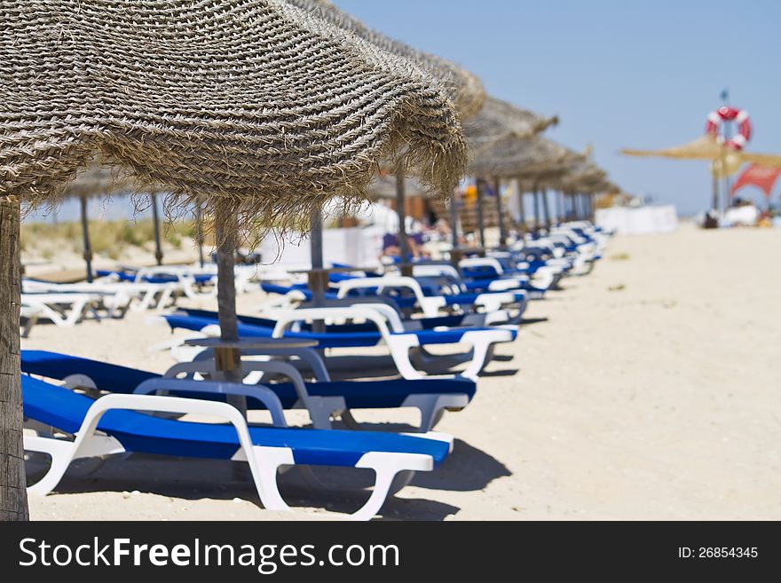 Beach chairs with straw umbrellas