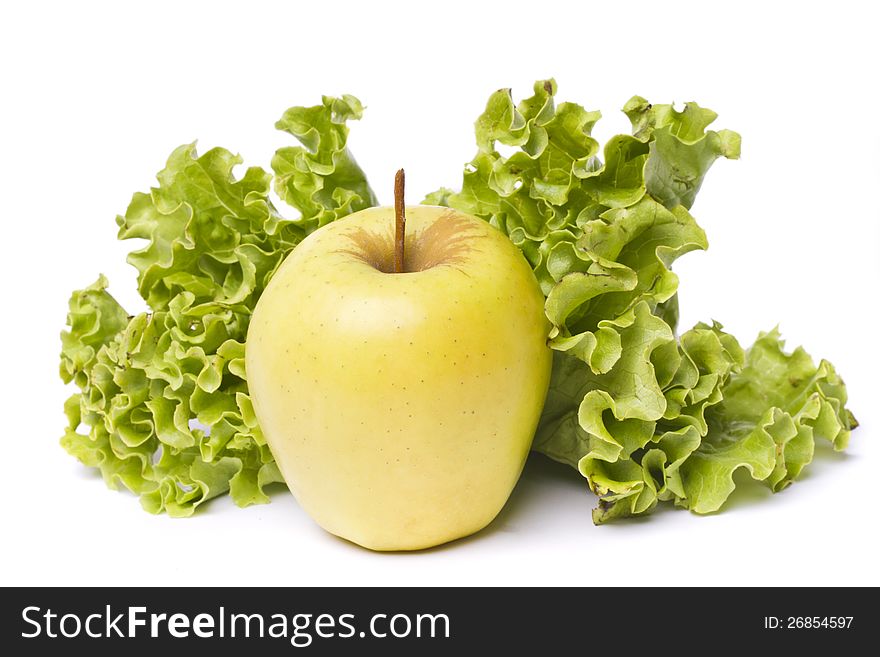 Close view of a tasty yellow apple with lettuce isolated on a white background. Close view of a tasty yellow apple with lettuce isolated on a white background.