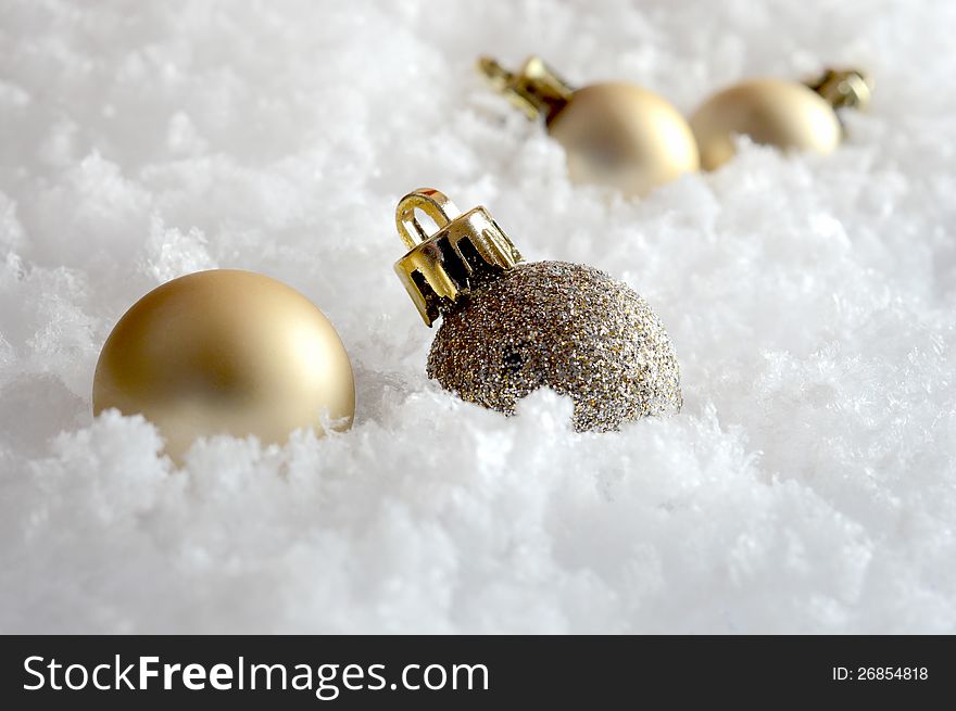 Macro of golden Christmas decorations buried in snow flakes. Copy space. Macro of golden Christmas decorations buried in snow flakes. Copy space.