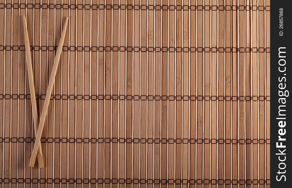 Two chopsticks on sushi mat background for menu. Two chopsticks on sushi mat background for menu