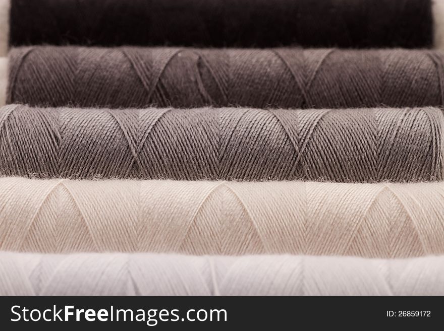 White, grey and black rolls of thread. Closeup, shallow depth of field. White, grey and black rolls of thread. Closeup, shallow depth of field.
