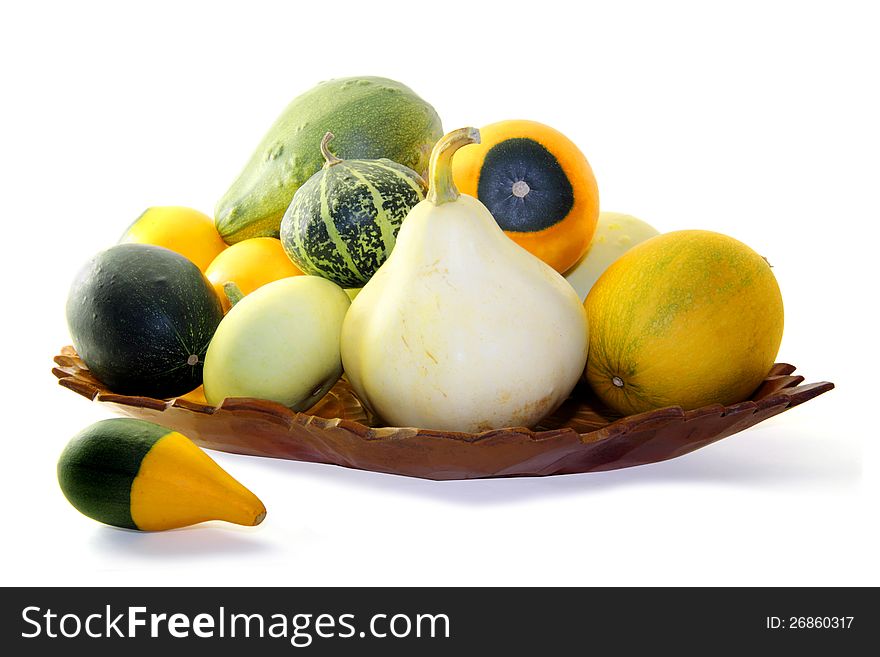 Wooden tray with small assorted gourds isolated on a white background