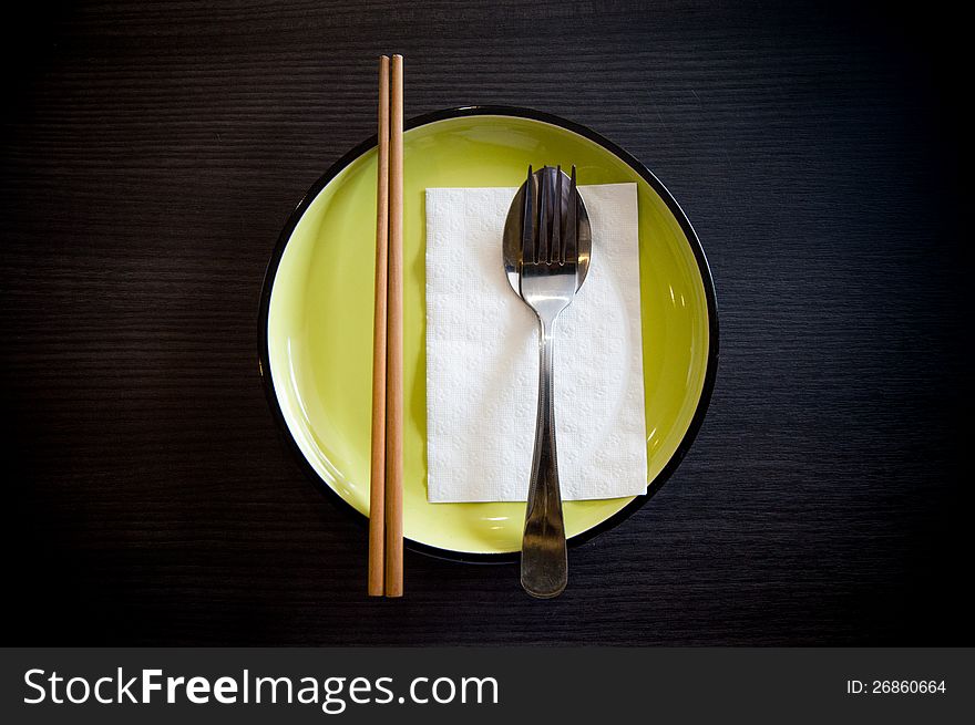 Dish set with chopsticks spoon fork napkin on green dish
