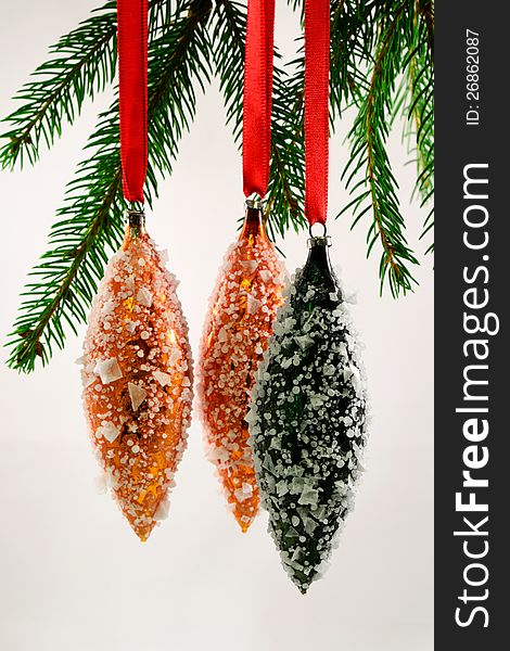 Three oval shaped  Christmas tree ornaments with false frost hanging. Three oval shaped  Christmas tree ornaments with false frost hanging