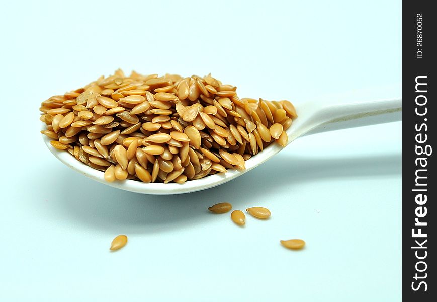 Golden flaxseed, displayed on a small white spoon. Flaxseed is great ingrediants for healthy foods.